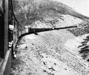 A man sticking his head out of a window of a railway car of a train traveling along the trans-siberian railroad in 1905, russia.
