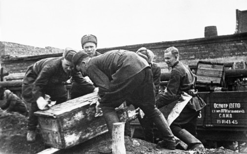 Men loading dismantled factory machinery onto railroad cars for evacuation to the urals, 1941.
