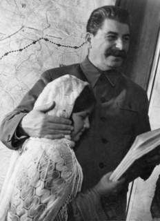 Propaganda photo of josef stalin as benevolent father figure with eleven year old mamlakat nakhangova, a schoolgirl from the lakhuti collective farm, stalinabad region, tajikistan soviet republic, kre...