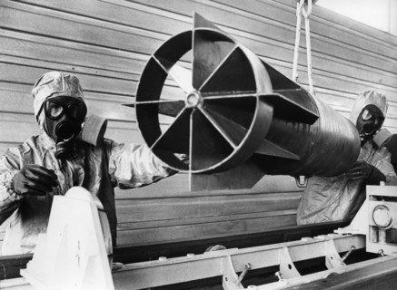 Technicians in protective suits lift empty case of chemical air bomb out of a discharge chamber after the chemical agent was drained,  soviet military base of shikhany, saratov region, ussr, october 4...