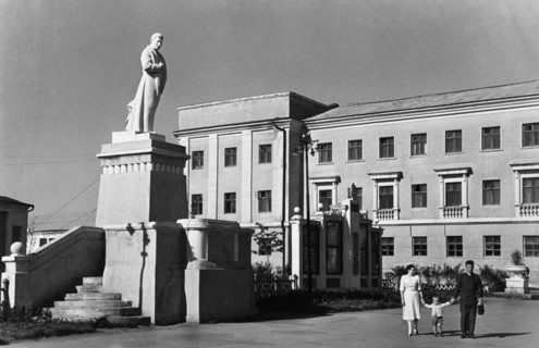 A family strolling under the benificent gaze of a sculpture of josef stalin, 'the great continuer of lenin's cause' on one of the central thoroughfares of stalinogorsk, in the moscow coal basin, ussr,...