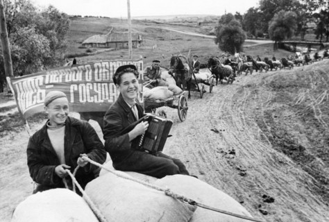 Harvest time on a collective farm in the ussr, august 1947, workers of the vakhitov collective farm taking grain to an elevator in the tatar autonomous soviet socialist republic, the banner reads 'bre...