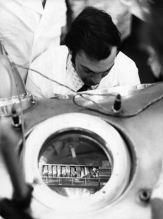 The ampule containing lunar soil and rock delivered by the re-entry module of the soviet lunar lander, luna 24, is being examined in a vacuum chamber by a scientist, it has been opened at the receivin...