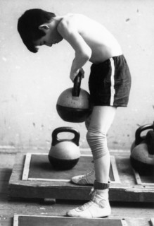 A young boy at the sambo-70 sports school lifting weights as he trains to be a sambo wrestler, russia, 1991.