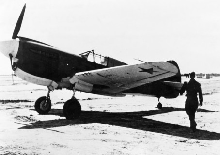 A russian pilot about to enter an american fighter plane (p-41?) that was just delivered, complete with red star insignia, to the red air force at an assembly center for u,s, lend-lease aircraft in ir...