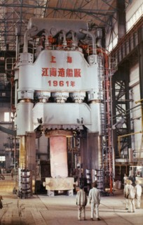 The 1,200 ton hydraulic press at the shanghai heavy plant in china in the early 1960's, it is pictured processing a 55 ton machine part of steel rolling equipment, made and designed in china, the pres...