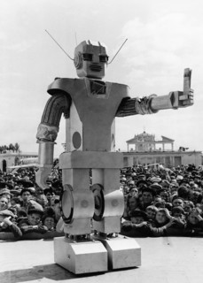 A 'robot' holding a copy of the soviet newspaper pravda, designed by youthful muscovites, kindly inviting visitors into the 'ussr electrification' pavilion of the ussr economic achievements exhibition...