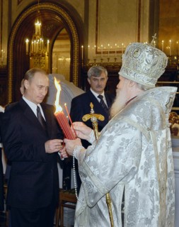 Patriarch of moscow and all russia alexy ll handing to president of russia vladimir putin a candle lit of the holy fire brought from jerusalem, at the easter service at the christ the saviour cathedra...