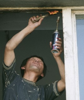 A north korean guest worker repairs a window, in vladivostok, russia, january 28 2003,russian businessmen like to hire foreign citizens (chinese, vietnamese, north koreans) who agree to work under any...