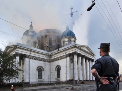 Policeman watching a fire at troitsky (trinity) cathedral being extinguished by a helicopter in st, petersburg, russia, august 25, 2006.