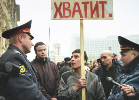 Moscow,russia, october 25 2002: policemen trying to pursuade a demonstrator with a slogan 'enough' in hand to stop his unauthorized protest action during the meeting which was organized by relatives o...