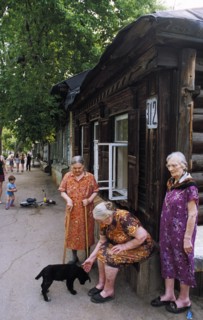 Elderly women in front of an old wooden house in a district in samara built in the19th century, russia.