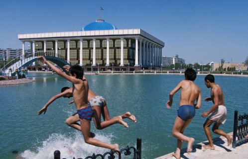 Boys swimming in a pool of a new park near the parliament building (in the background) in tashkent, uzbekistan, 1990s.