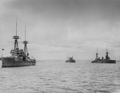 Black and white image of ships moored in the ocean under a cloudy sky