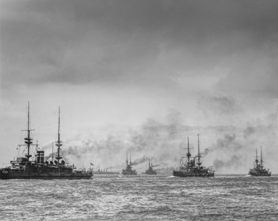 Historic black and white image of ships on the ocean under a cloudy sky