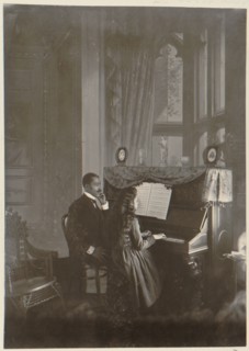 African American man giving piano lesson to young African American woman