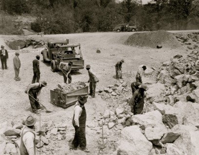 Prisoners breaking up rocks at a prison camp or road construction site