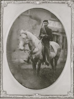 Unidentified African American soldier seated on horseback, facing left.