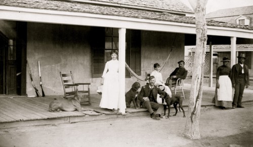 Two soldiers and two women on porch, with Afro-American woman and man to right, Fort Verde, Arizona