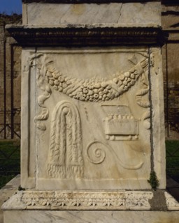 South side depicting a garland of flowers, a chest for incense, the curved cane of the augur and a tablecloth.