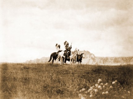 Edward S. Curits Native American Indians - Three Sioux Indians of horseback on plains with rock formation in background circa 1905.
