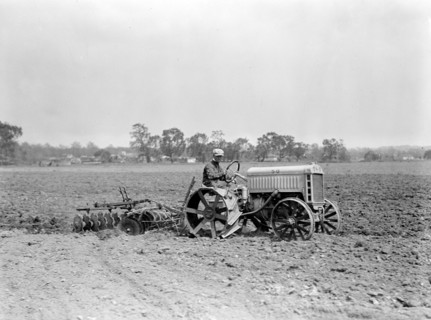 Farmer driving Ford Tractor in field circa 1917.