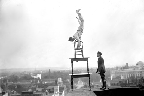 J. Reynolds Acrobat, performing acrobatic and balancing acts on top of building above 9th Street NW in Washington D.C. circa 1917.