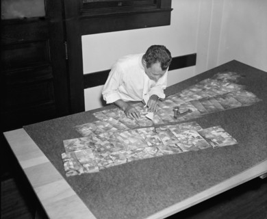 Map maker fitting together photos for the final map circa 1937.