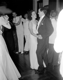 A happy couple dancing at a reception circa 1937 .