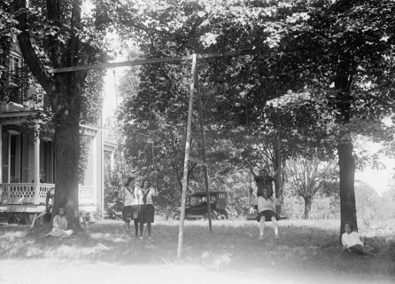 Children having fun and playing on a swing set at a YWCA camp circa 1919 .