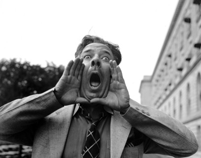 Close up of a man practing his hog calling, but looking like an angry man circa 1937.