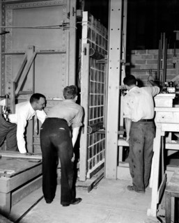 Workers at the National Bureau of Standards testing the strength of  glass panels circa 1938 .