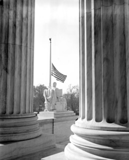 Scene thru the pillars of the U.S. Supreme Court Building showing the flag at half-mast out of respect to Justice Pierce Butler, who died this morning after a long illness circa November 1939 .