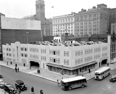 Street scene with buses, cars and pedestrians outside Star Parking Plaza in Washington D.C. circa 1940 .