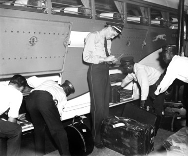 Workers at Greyhound bus station loading and checking baggage circa 1937.
