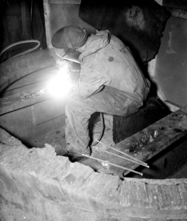 Factory worker welding a piece of metal circa 1936.