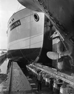 Dutch man stands between two ships in a shipyard or dock circa October 20, 1947.