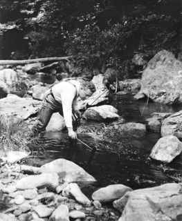 A man fishing in a river circa 1932.