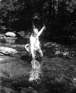 A man fishing in a river circa 1932.