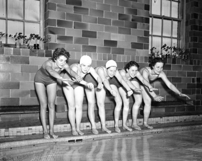 Women swimmers preparing to dive into a swimming pool circa 1936.