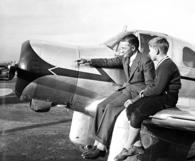 Man and his son sitting on the wing of a Curtiss airplane circa 1936.