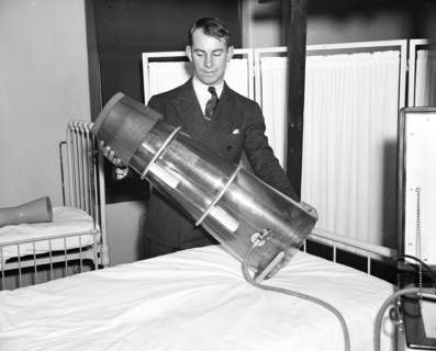 Leg saver. Chester Antos, student at Georgetown University medical school, photographed with the newly devised Emerson suction pressure apparatus which designers believe will prevent amputation in man...