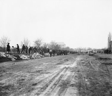 Men filling sandbags and placing them to protect an area of Washington D.C. during flooding of the  Potomac River, Washington, D.C. circa March 19, 1936 .