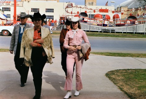 1960 Ft. Worth Stock Show - Well dressed visitors to the Fort Worth Stock Show - Tilt-a- Whirl amusement ride in the background.