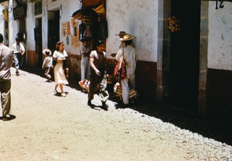 Locals walking down a street in a city in Mexico circa 1950-1955.