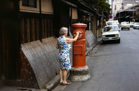 Woman mailing letters in a postal service mailbox in Kyoto Japan circa 1976.