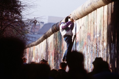 A West German man uses a hammer and chisel to chip off a piece of the Berlin Wall as a souvenir.  A portion of the Wall has already been demolished at Potsdamer Platz..