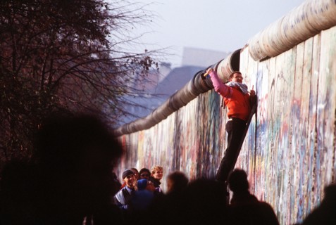 A West German man uses a hammer and chisel to chip off a piece of the Berlin Wall as a souvenir.  A portion of the Wall has already been demolished at Potsdamer Platz..