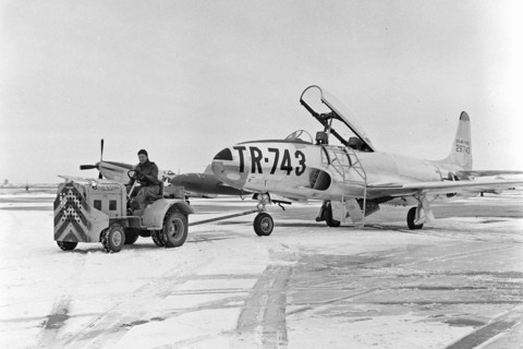 A T-33 aircraft is towed on the flight line