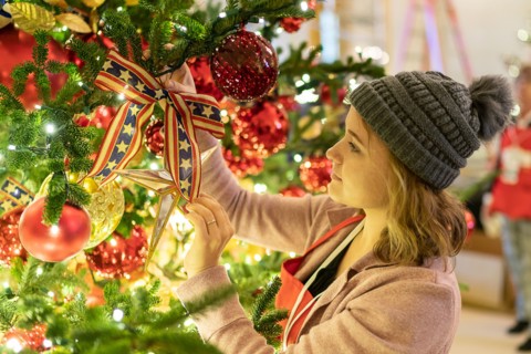 A volunteers decorates a tree in the East Room of the White House